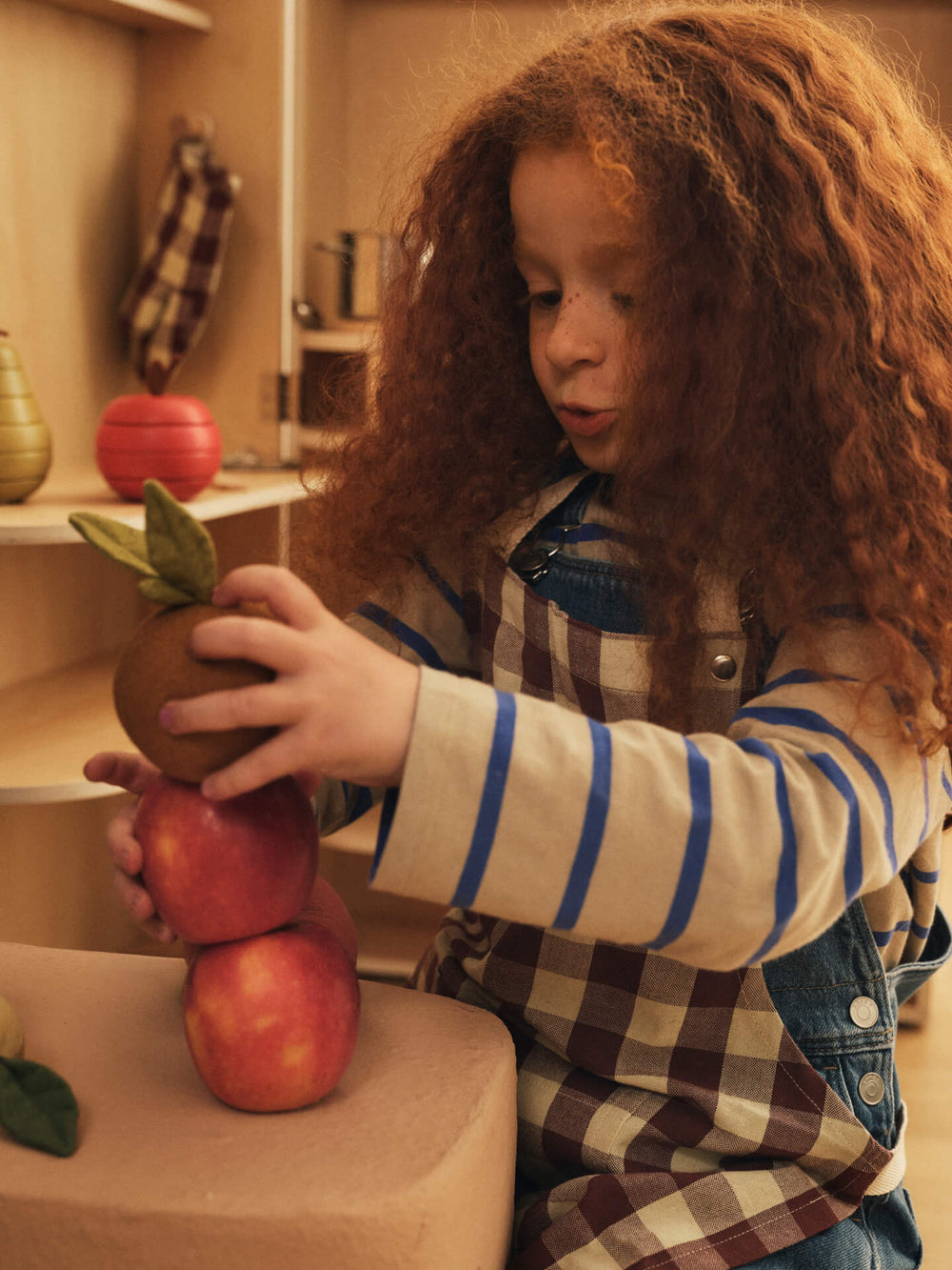 Child stacking the soft play fruits into a tower on a table