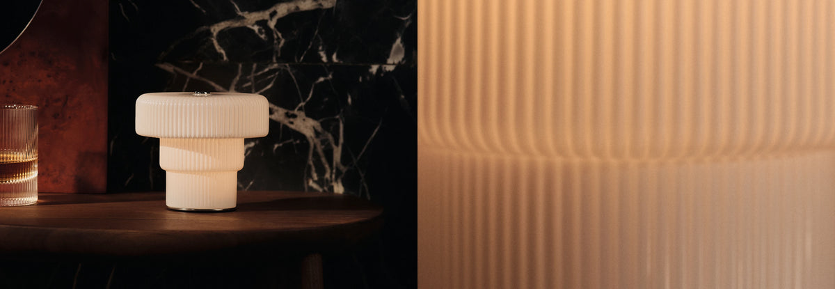 Sale lighting collection, lit fluted table lamp on a side table beside a glass, with close-up of its ribbed shade